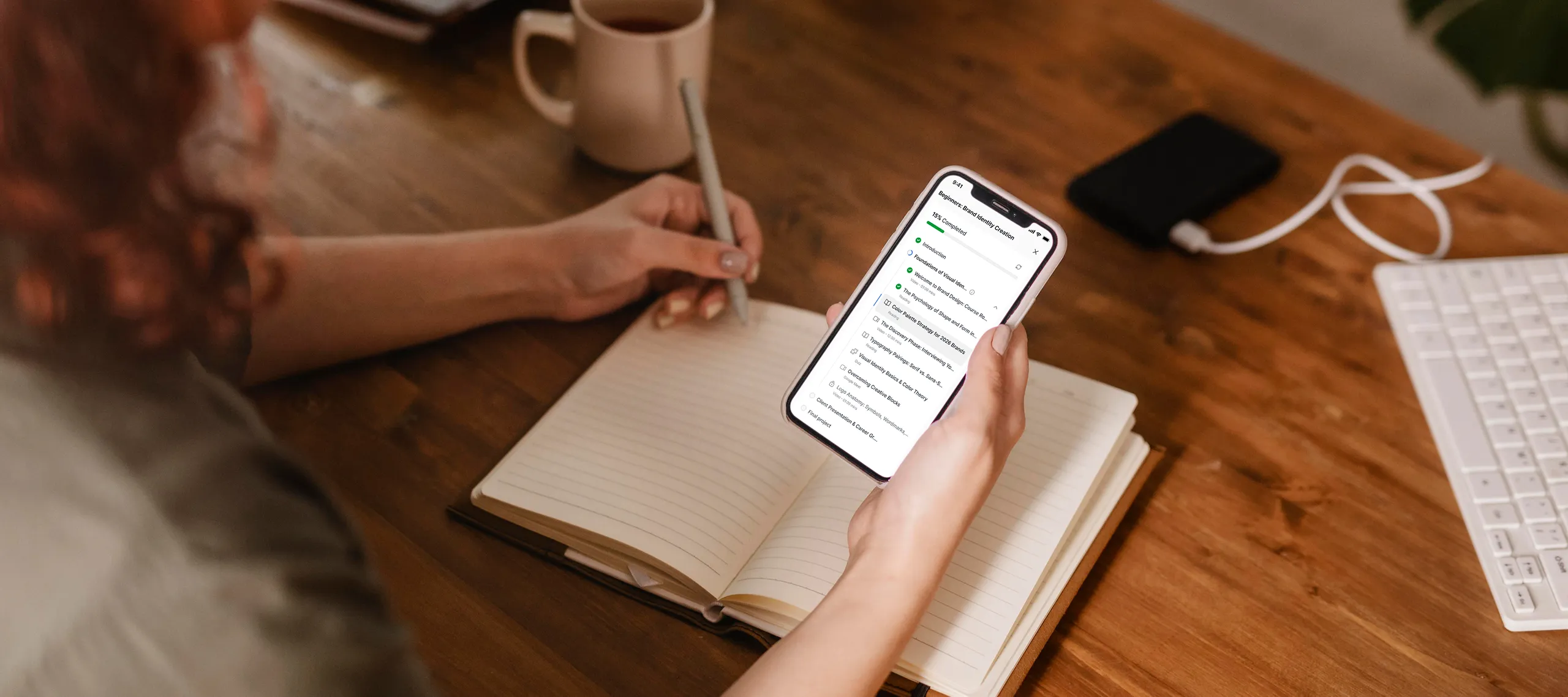 Student checking course progress on smartphone while writing