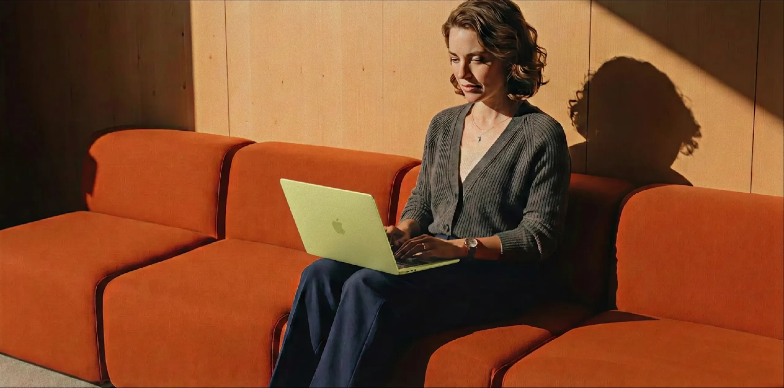An instructor works on a yellow MacBook from a warm, modern lounge setting, with four feature callouts below highlighting TutorLMS analytics capabilities — student management, review management, new user tracking, and CSV data export — showing how platform owners can manage and monitor their entire academy from one place.