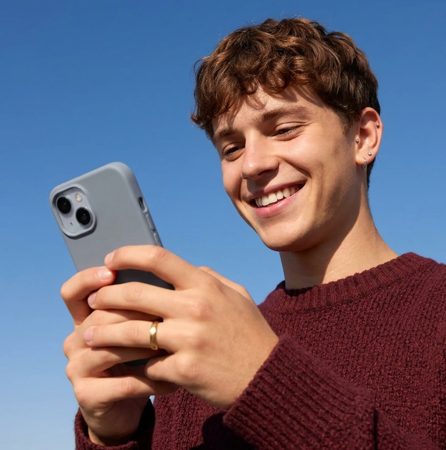 A young guy looking a phone and smiling
