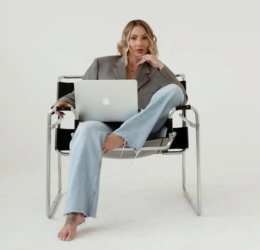 A solo creator woman sitting on a chair with a macbook on