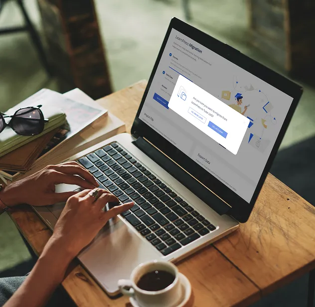A person types on a laptop at a wooden café table with a coffee cup nearby, with a LearnPress Migration confirmation dialog open on screen asking to migrate to TutorLMS — alongside a 3-step migration process panel showing Install, Backup, and Start steps on the right.